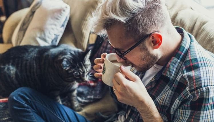 Drinking Coffee with Cat Man drinking coffee on the couch with cat
